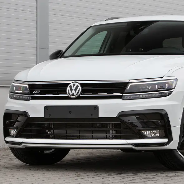 Close-up of the front of a white Volkswagen SUV at Holland's Highline Automotive, showing the VW logo, grille, headlights, and bumper—your trusted spot for Volkswagen repair in Bridgewater, MA. Parked on a paved surface before a metal garage door.