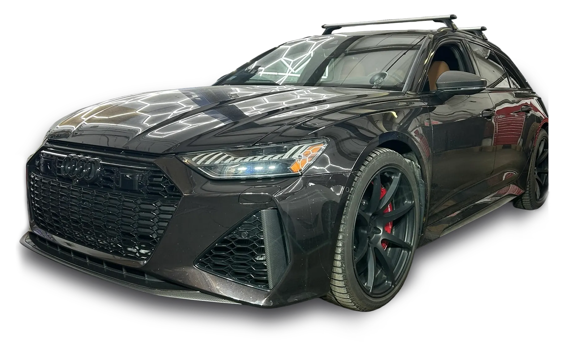 A sleek black Audi RS6 Avant wagon, a standout European vehicle with sporty black wheels, red brake calipers, and roof rails, is shown from a low front-side angle against a black background.